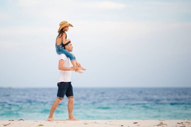 Baba ve kızı sahilde omuz omuza yapıyor.