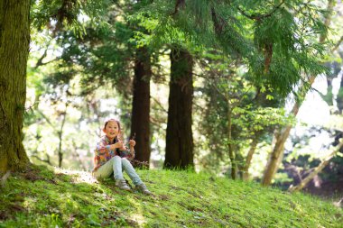 bir ormanda oturan küçük kız