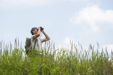 Dürbünle uzaklara bakan bir adam.