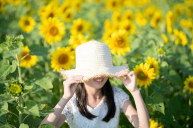 Ayçiçeği tarlasında şapkalı bir kadın.