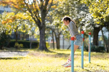 Sonbahar parkında yatay barda oynayan kız