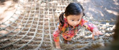 Küçük Asyalı çocuk parka tırmanıyor. 