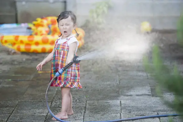asian girl playing with water  hose in the garden
