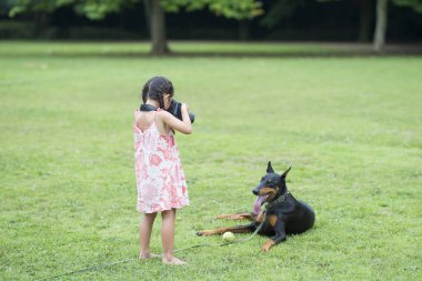 Yazın parkta köpeğinin fotoğrafını çeken bir kız.