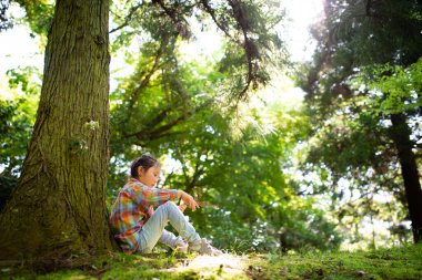 Yeşil bir parkta, ağaçların yanında küçük sevimli Asyalı kız.