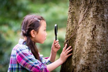 Büyüteçle gözlemleyerek kız
