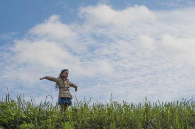 Küçük tatlı Asyalı kız yeşil çimenlerde eğleniyor.