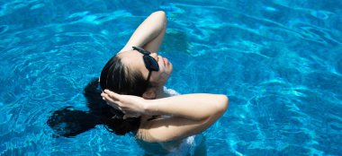 Havuzda yüzen genç bir kadın.