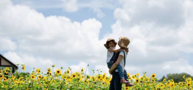 Anne ve kızı ayçiçeği tarlasında oynuyorlar.