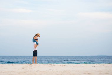 Baba ve küçük kızı kumlu deniz sahilinde