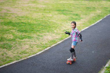 little girl riding a skateboard in the park