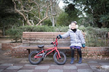 Parktaki bankta bisikletli Asyalı çocuk
