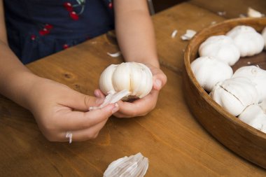 Çocuk eli sarımsağı soyuyor.