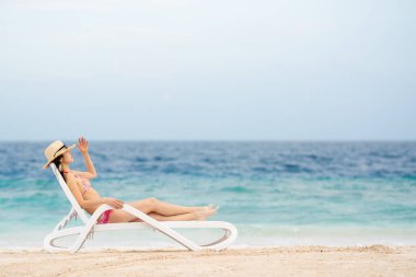 Genç bir kadın sahilde dinleniyor.