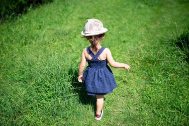 Parkta yürüyen elbiseli küçük kız..