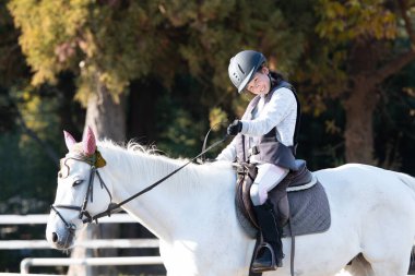 Beyaz atın üzerindeki tatlı Asyalı küçük kız