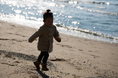 Kumsalda koşan tatlı Asyalı küçük kız.