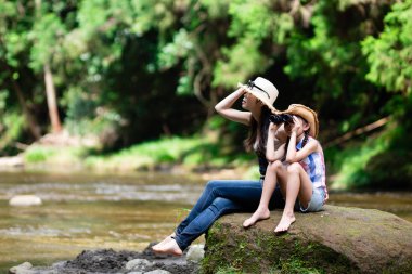 Anne ve kızı, dağ akarsularında dürbün kullanıyorlar.