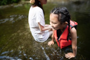 Anne ve kızı dağ deresinde oynuyorlar.
