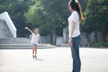 Elini sallayarak bir kadına doğru koşan bir kız.