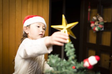 Noel 'de Noel ağacı süsleyen küçük tatlı Asyalı kız..