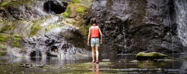 Genç bir kız nehirde duruyor.