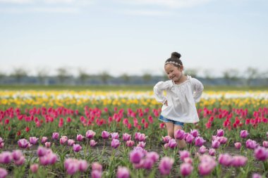 Tatlı Asyalı kız lale tarlasında eğleniyor.