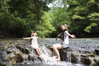 Anne ve kızı dağ deresinde oynuyorlar.