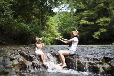 Anne ve kızı dağ deresinde oynuyorlar.