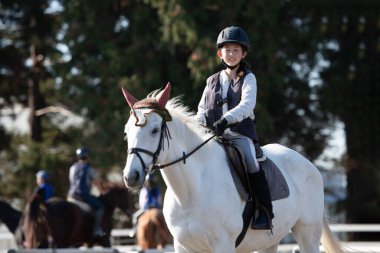 Küçük tatlı Asyalı kız ata biniyor.
