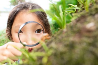 Kız büyüteçten bakıyor  