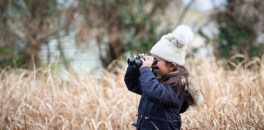 Sonbaharda tarlada dürbünle dürbünle bakan genç bir kadın.