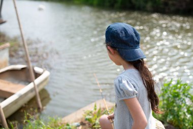 Küçük kız iskelede balık tutuyor. 