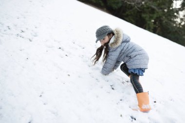 Karlı parkta oynayan kız.