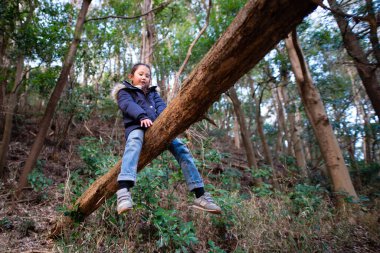 Mutlu küçük kız ağaca tırmanıyor.