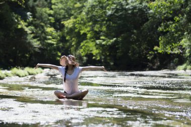 Genç bir kadın nehirde oynuyor.