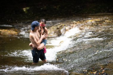 Baba ve kızı dağ deresinde oynuyorlar.