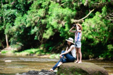 Anne ve kızı, dağ akarsularında dürbün kullanıyorlar.