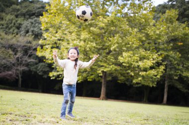 Küçük kız çimenlerde futbol oynuyor. 