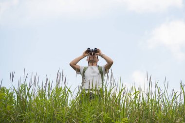 Dürbünle uzaklara bakan bir adam.