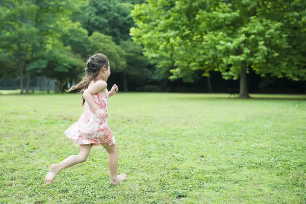 Parkta koşan küçük tatlı Asyalı kız.