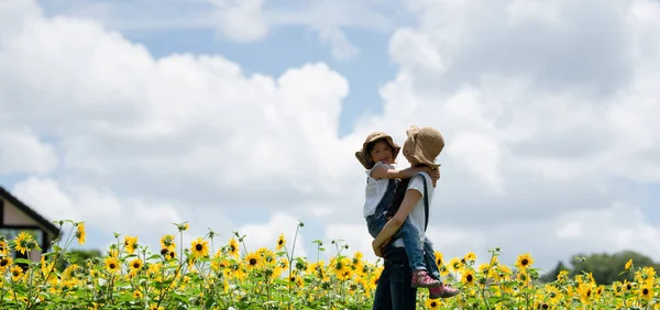 Anne ve kızı ayçiçeği tarlasında oynuyorlar.