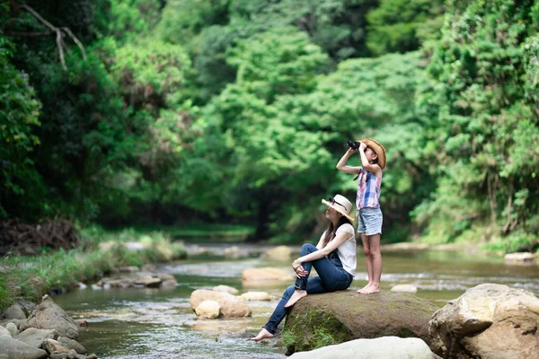Anne ve kızı, dağ akarsularında dürbün kullanıyorlar.
