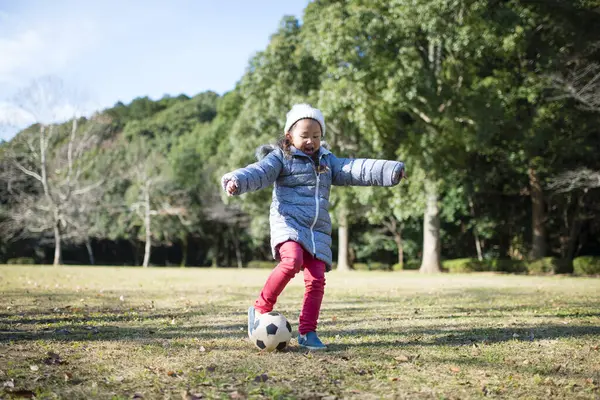 Parkta top oynayan Asyalı küçük kız.