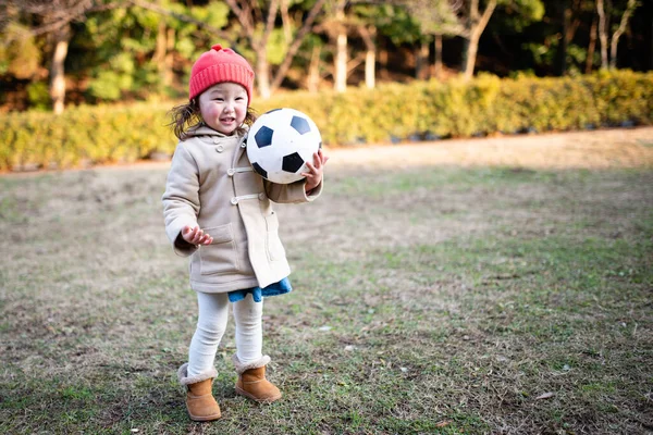 Çimlerin üzerinde topu olan küçük bir kız