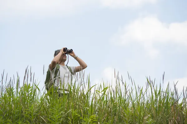 Dürbünle uzaklara bakan bir adam.