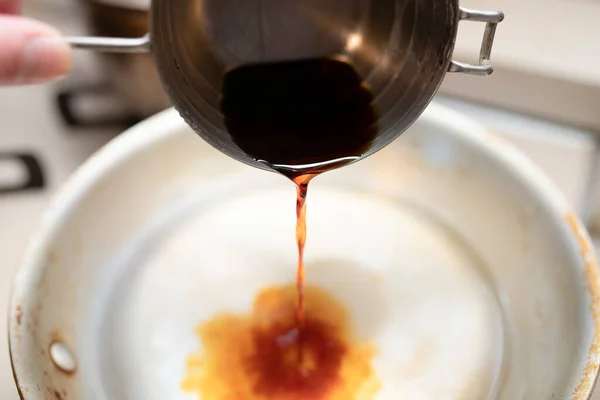 Pour soy sauce from the measuring cup into the pot