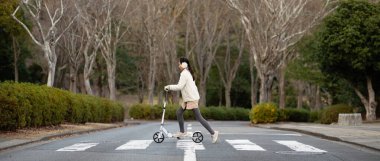 Parkta scooter süren Asyalı kız.