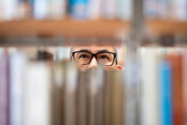 Kitap seçen gözlüklü bir adam.