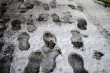 Karda bir sürü ayak izi olan bir kaldırım.